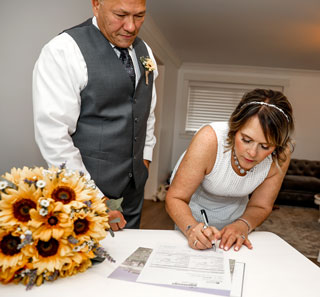Bride and groom signing next to sunflower bouquet