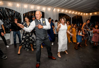Family dancing at sunflower wedding in reception tent