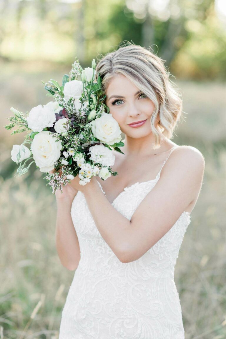 Romantic blush wedding bride in field with bridal bouquet