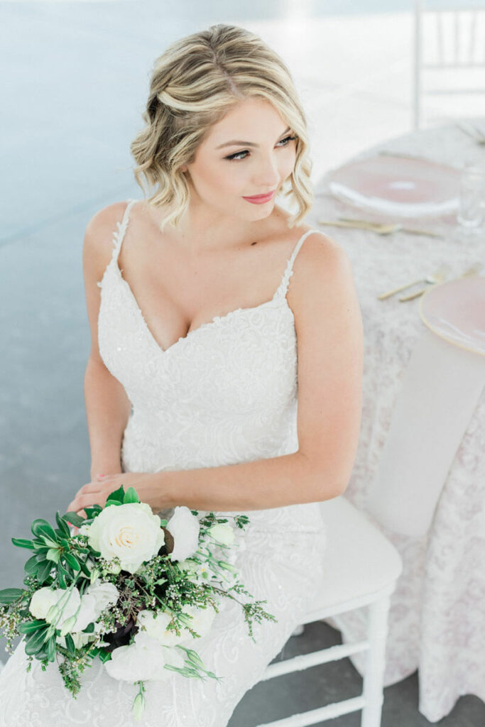 Romantic blush wedding bride with bouquet at reception table