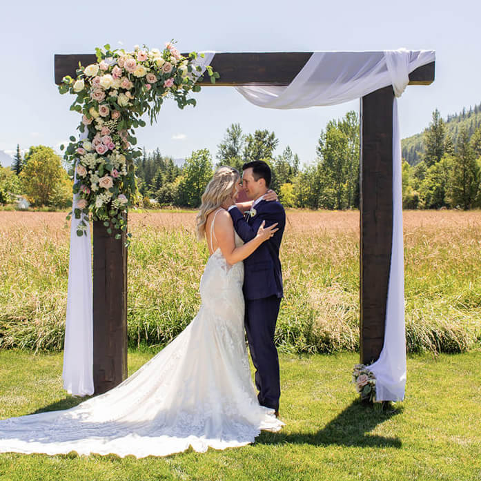 Bride and groom kissing under arbor at Mount Peak Farm