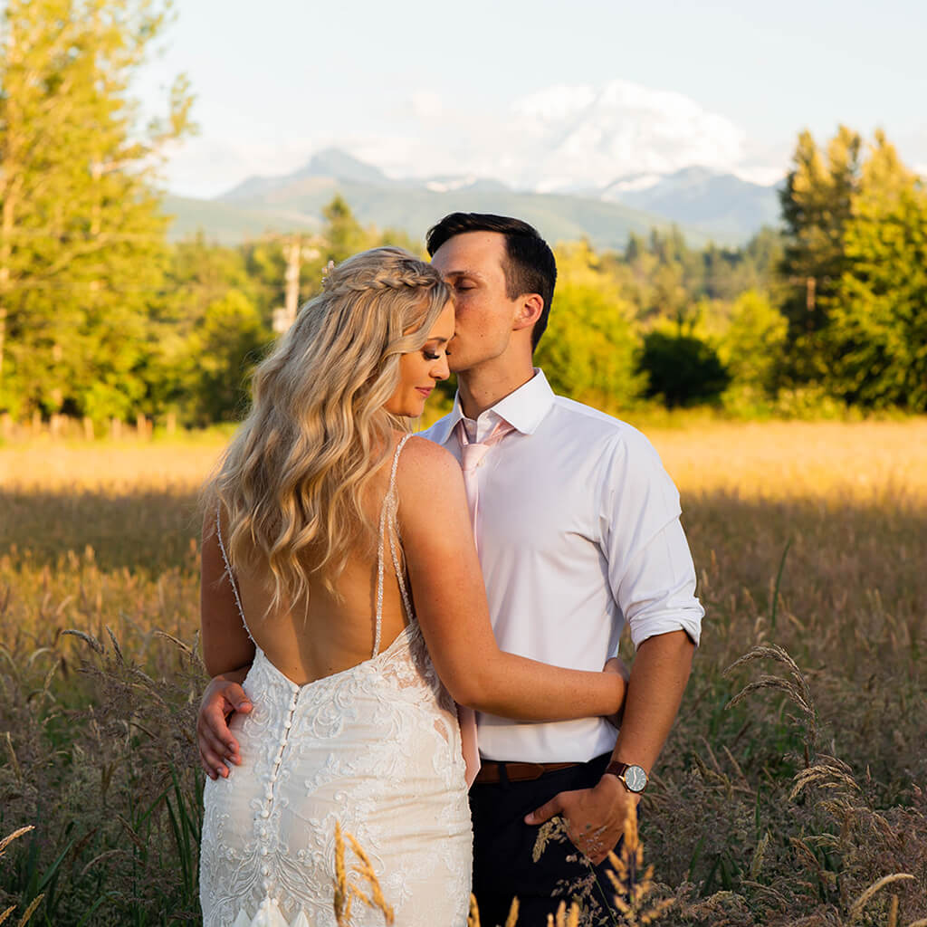 Wedding couple in hayfield with Mt. Rainier in background