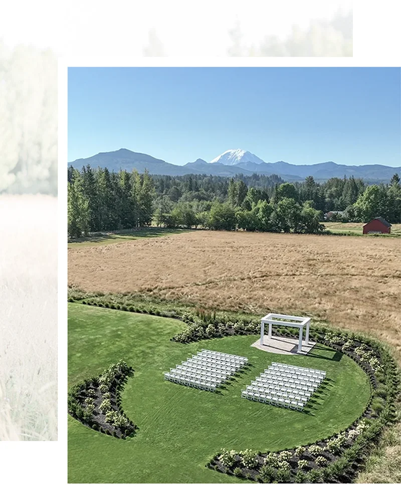 Ceremony white arbor surrounded by formal hedge and white hydrangea landscaping with a hayfield and Mount Rainier backdrop.