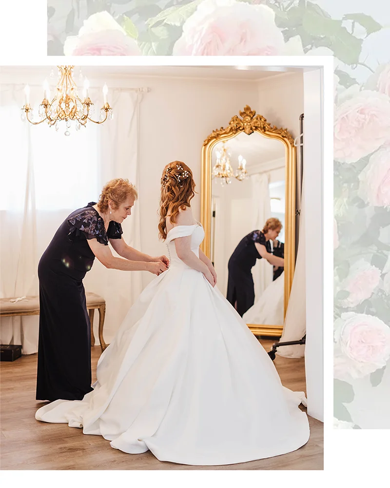 Bridesmaid helping bride with gown. Bride looking in gold mirror under chandelier in bridal cottage at Mount Peak Farm